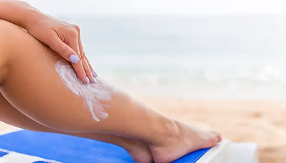 往腿上涂防晒霜的女子图片素材(JPG)